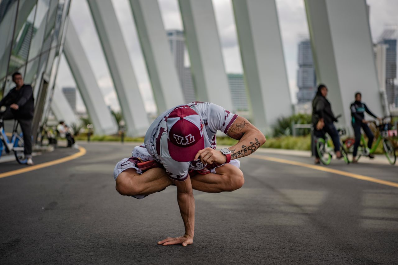 A person performing a yoga pose in an urban setting, surrounded by modern architecture.
